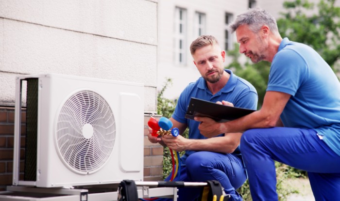 HVAC technicians reviewing an outdoor air conditioning unit in Johnstown, CO