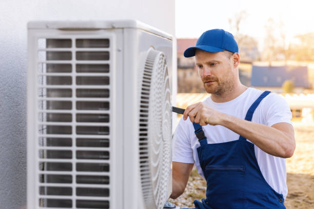 HVAC technician servicing an outdoor air conditioning unit in Johnstown